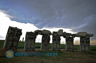 A weak storm looms over Carhenge on May 25.