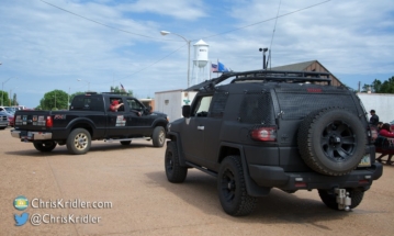 A couple of storm chasing cars with the Wakita water tower in the background.