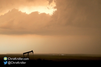 An oil pump jack keeps working as the storm slides by.