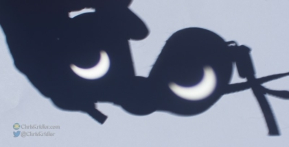 Binoculars make cartoon eyes as they project the crescent sun.