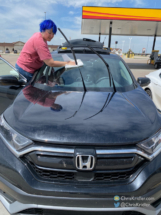 Alethea applies RainX to the windshield in Sidney pre-chase.