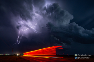 The lights of a passing truck frame the lightning storm.